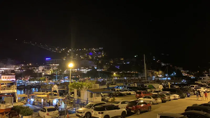 night view of kas seaside and boats are docked to the harbor and people strolling around