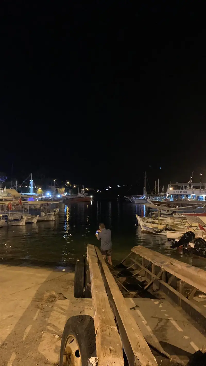 yachts docked in marina at night and a man taking pictures 