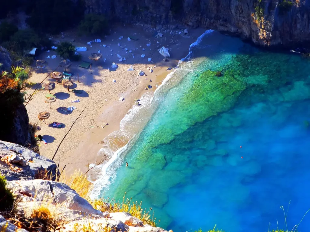 Image of the serene beach in Butterfly Valley, Fethiye, with crystal clear waters and surrounded by rugged cliffs."