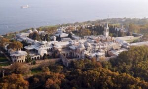 An aerial view of Topkapi Palace in Istanbul, with its historic buildings and courtyards surrounded by greenery and overlooking the sea.